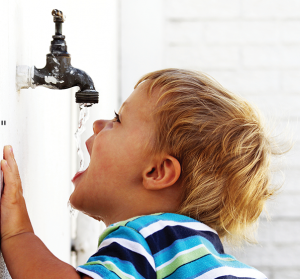 Niño bebiendo agua de un grifo antiguo